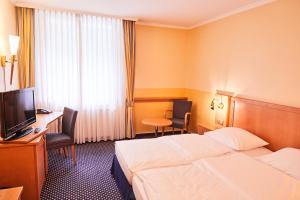 a hotel room with a bed and a desk and a television at Hotel Cap Polonio in Pinneberg