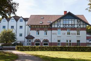 a large white building with a red roof at Hotel Cap Polonio in Pinneberg