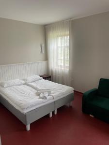 a bedroom with a white bed and a green chair at A. Smetonos Dvaro Smetonienės svetainė 