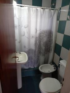 a bathroom with a shower curtain with a toilet and a sink at Complejo Aguas Termales in Gualeguaychú