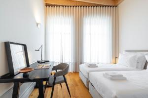 um quarto de hotel com uma secretária e uma cama e uma cama e uma secretária em Mouzinho Village River em Porto