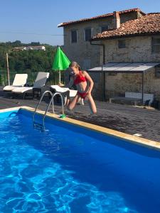 Casa In Bocca Al Lupo في Clavesana: فتاة صغيرة تقفز في حمام السباحة