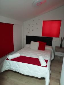 - une chambre avec un grand lit blanc aux accents rouges dans l'établissement ALOJAMIENTO RURAL EL CARRIL, à Pegalajar