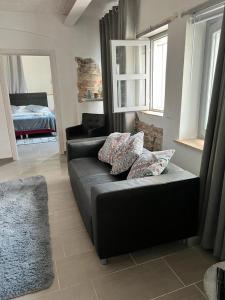 ein schwarzes Sofa im Wohnzimmer mit einem Bett in der Unterkunft Casa In Bocca Al Lupo in Clavesana