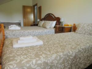 um quarto com 2 camas e toalhas brancas em Cantinho do Mel em Castro Daire