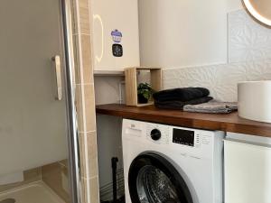 een wasmachine in een badkamer met een aanrecht bij Appt centre de Courseulles - 100m de la plage in Courseulles-sur-Mer