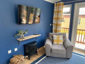 a living room with a chair and a television on a blue wall at River View Lodge in Felton
