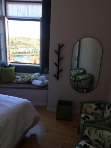 1 dormitorio con espejo, cama y ventana en Ilha 12 Suites en Coimbra
