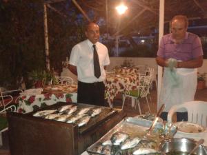 two men standing in front of a grill with fish at Hotel Europa in Ischia