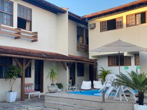 a patio with chairs and an umbrella next to a building at Pousada Rancho Verde in Porto Seguro