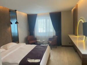 SarıkamısにあるSnowflake Dag Hotel & SPAのベッド、テーブル、椅子が備わるホテルルームです。