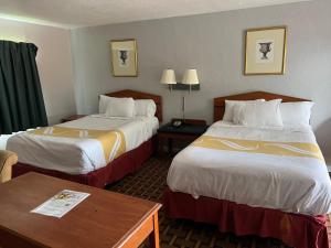 una camera d'albergo con due letti e un tavolo di Budget Inn a Tallahassee