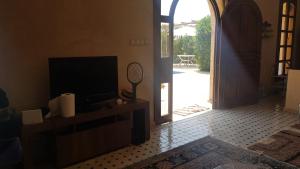 a living room with a television and an open door at Gîte avec piscine privé in Agadir