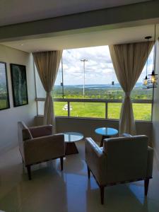 a living room with two chairs and a large window at Motel Colorado (Adult Only) in Brasília