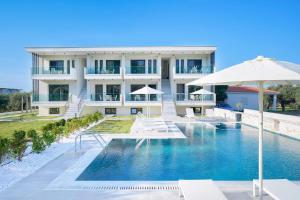 un hotel con piscina y sombrilla en Olia Thassos - Luxury Apartments, en Limenas