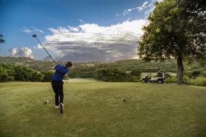 Ein Mann, der einen Golfklub auf einem Golfplatz schwingt. in der Unterkunft El Conquistador Resort - Puerto Rico in Fajardo