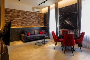 a living room with a couch and a table with red chairs at Lofty Exclusive Apartments in Sarajevo