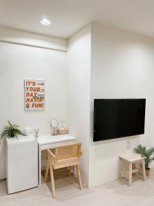 a living room with a tv on a white wall at HoHo Woo Tainan Homestay in Tainan
