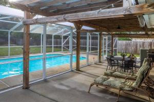 um pátio coberto com uma piscina, uma mesa e cadeiras em Pool House, Short Drive to Beach, Grill, Smart TV em Navarre