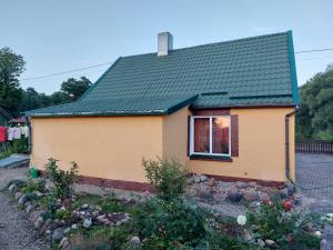 une petite maison jaune avec un toit vert dans l'établissement Camping Camino Latvija 2 person room WIFI or space for tent or camper, à Žagarė