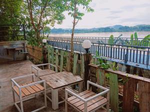 une table en bois et deux chaises à côté d'une clôture dans l'établissement ไทยกันเอง ริมโขง, à Chiang Khan