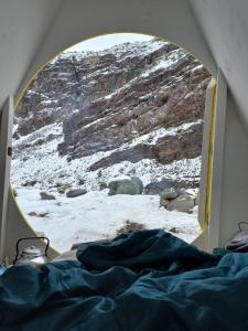 una finestra con letto e vista su una montagna di Glamping Roots del Yeso a Los Chacayes