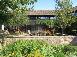 una casa con un muro di pietra e alberi e fiori di Combe Lancey Farmhouse B&B a Crediton