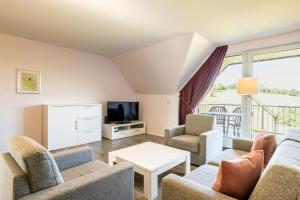 ein Wohnzimmer mit einem Sofa, Stühlen und einem TV in der Unterkunft Gemünder Ferienpark Salzberg in Schleiden