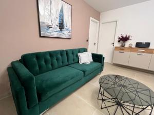 ein grünes Sofa im Wohnzimmer mit einem Tisch in der Unterkunft ZADAR Panorama Sea View Apartments in Zadar