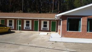 a brick house with green doors in a parking lot at Murphy Motel in Letitia