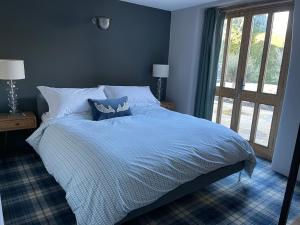 a blue bedroom with a bed and a window at 17th Century Barn near Le Manoir aux Quat’Saisons in Great Milton