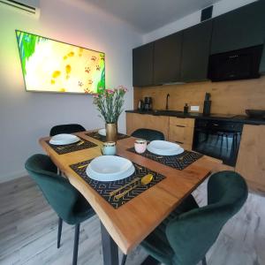 una mesa de madera con sillas verdes y una cocina en Haus am Meer Dziwnówek en Dziwnówek