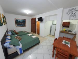 ein Schlafzimmer mit einem Bett und einem Tisch sowie eine Küche in der Unterkunft Charaí Lodge in Puerto Iguazú