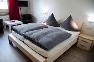 Bett mit grauen Kissen auf einem Zimmer in der Unterkunft Hotel Theile garni in Gummersbach