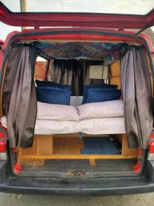 a bed in the back of a van with the back door open at VW Campervan in Pembrokeshire