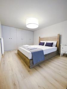 een witte slaapkamer met een groot bed met blauwe kussens bij SIBL LOFTS in Thessaloniki