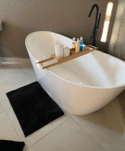 eine weiße Badewanne im Bad mit Waschbecken in der Unterkunft Charli’s Lodge in Mpheleng