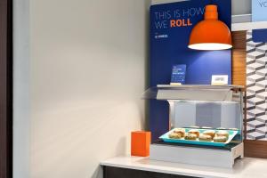 a display case with donuts on a shelf at Holiday Inn Express & Suites Greenville-Downtown, an IHG Hotel in Greenville