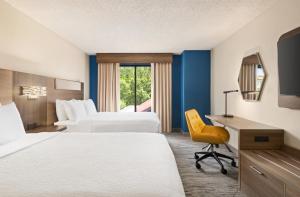 Holiday Inn Express & Suites Greenville-Downtown, an IHG Hotel في غرينفيل: غرفة فندقية بسريرين ومكتب وكرسي