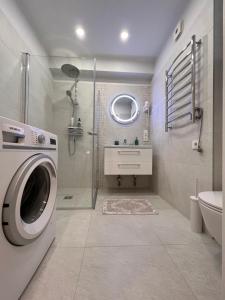 uma casa de banho com uma máquina de lavar roupa e um lavatório em Bell Tower Apartment em Plungė