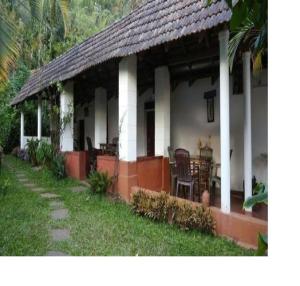 a white house with a table and chairs on it at Athithi Homestay by StayApart in Avathi