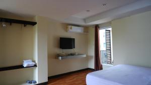 a bedroom with a bed and a tv and a window at Airport A1 Hotel in Chiang Mai