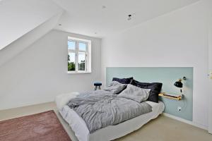 a white bedroom with a bed and a window at Sunny 1st floor apartment in Tisvildeleje