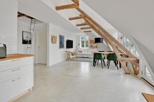 a kitchen and living room with a staircase and a table at Sunny 1st floor apartment in Tisvildeleje