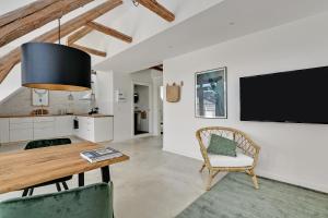 a kitchen and dining room with a table and a tv at Sunny 1st floor apartment in Tisvildeleje