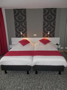 a bedroom with a bed with red and white sheets at Hotel Limburgia in Kanne