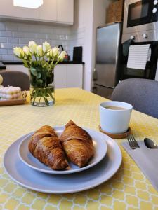 einen Teller Croissants auf einem Tisch mit einer Tasse Kaffee in der Unterkunft Nowoczesny apartament w sercu Wrocławia in Breslau