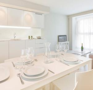 プラヤ・デアロにあるDaro Apartmentsの白いキッチン(テーブルの上にグラスと皿付)