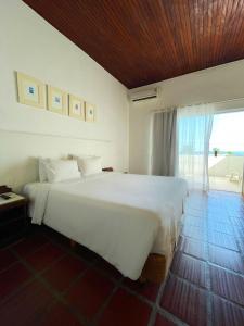 duże białe łóżko w pokoju z oknem w obiekcie Delphin Beach Hotel w mieście Guarujá