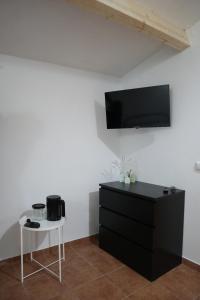 Habitación con tocador negro y TV en la pared. en Casa do Arco - Casa de Campo en Mezio